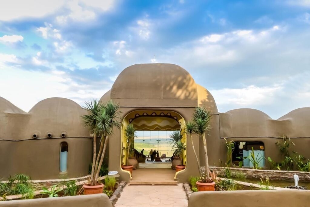 De ingang van de Mara Serena Safari Lodge, met koepelvormige lemen muren, open naar de savanne van de Masai Mara
