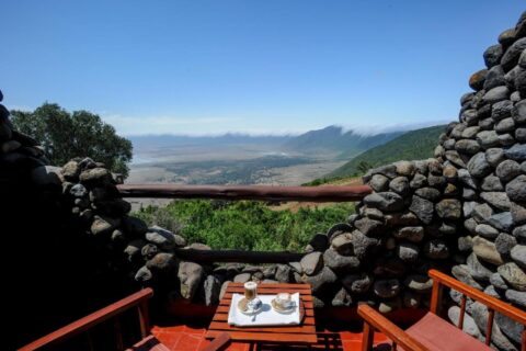 Twee kopjes koffie op een balkon van de Ngorongoro Serena Safari Lodge, tussen stenen muren, boven de krater