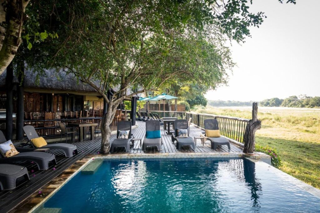 Het zwembad van de Umkumbe Safari Lodge en het houten terras, boven de grazige rivieroever
